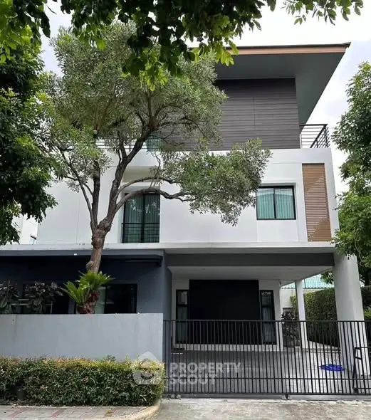 Modern three-story house with sleek design and lush greenery