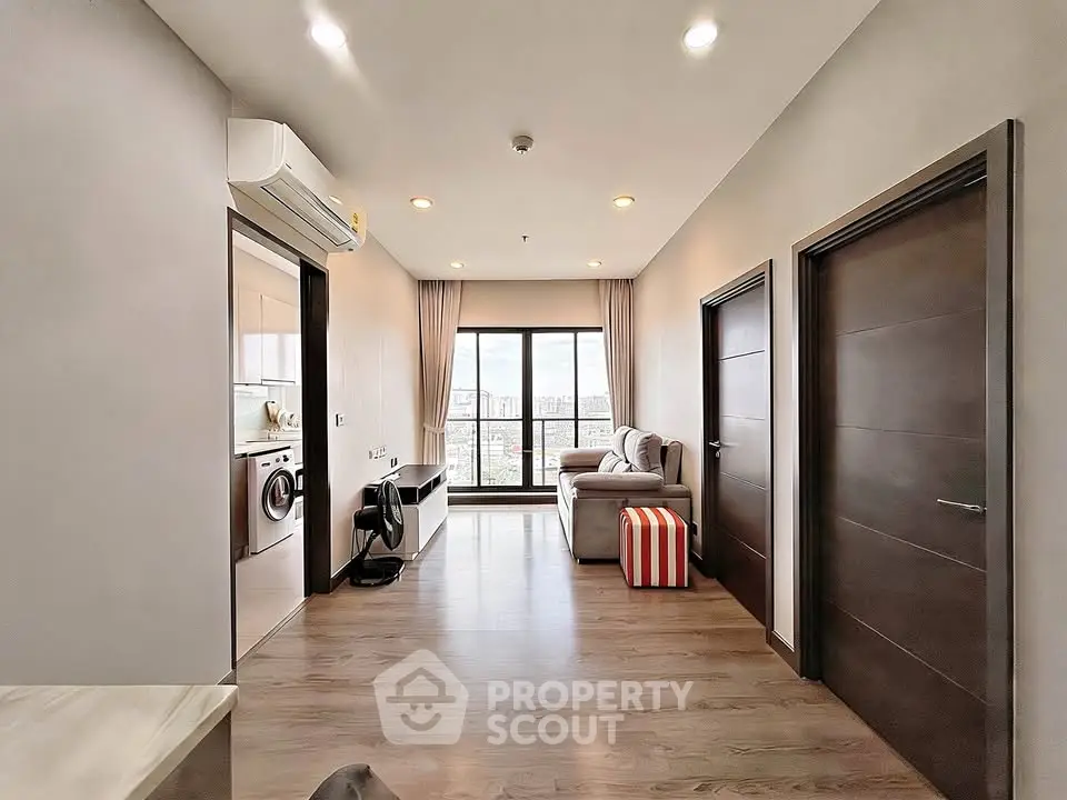 Modern apartment interior with spacious living room and city view, featuring sleek wooden flooring and contemporary furniture.