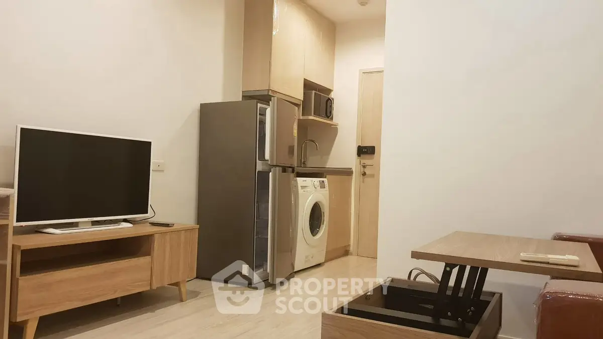 Modern apartment interior with TV, fridge, and washing machine in cozy living space.