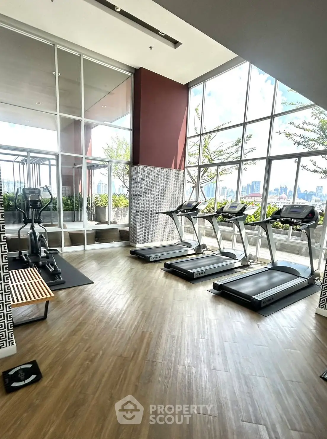 Modern gym with treadmills and city view in luxury apartment building