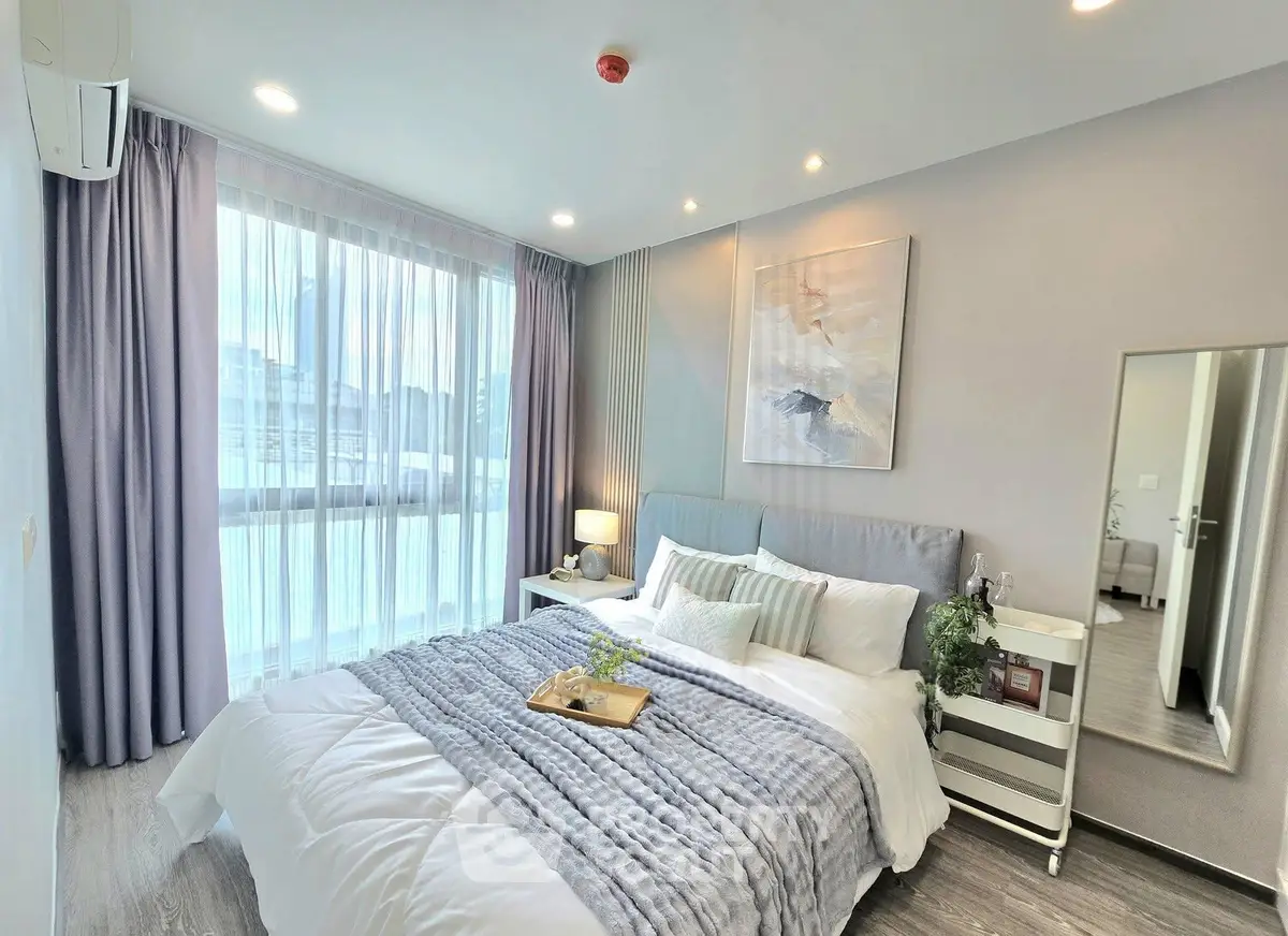 Elegant bedroom with modern decor, large window, and cozy bedding in a stylish apartment.
