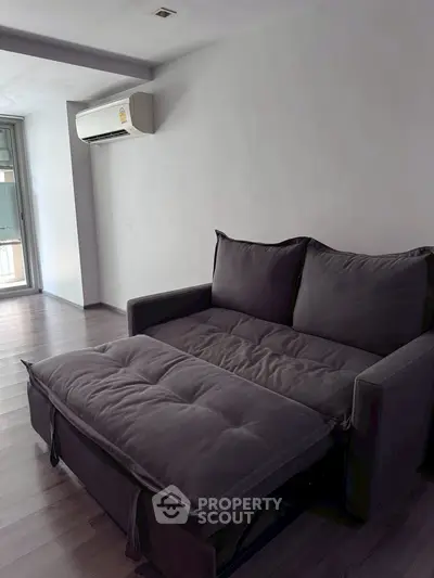 Modern living room with sleek dark sofa bed and air conditioning, perfect for urban living.