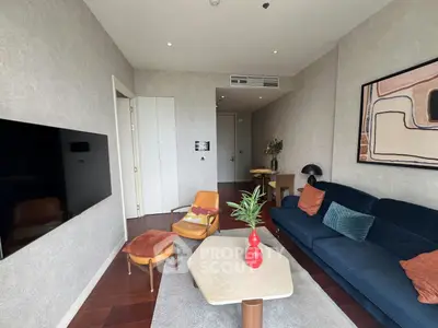Modern living room with stylish furniture and wall art, featuring a cozy blue sofa and sleek wooden accents.
