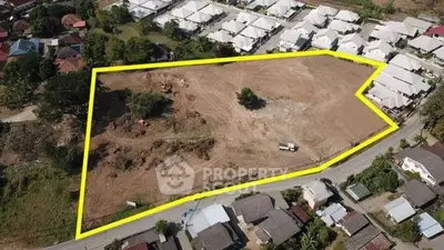 Aerial view of a large plot of land marked for development in a residential area.