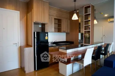 Modern kitchen with sleek wooden cabinetry and dining area in open layout apartment.
