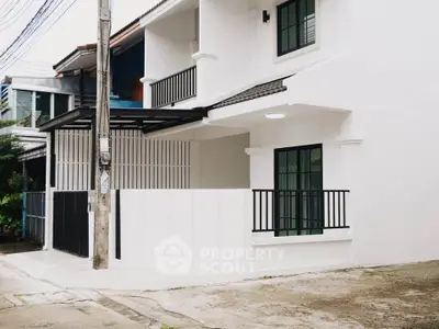 Modern white townhouse exterior with black accents and spacious balcony.