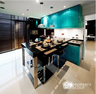 Sleek modern kitchen with vibrant turquoise cabinets, stainless steel appliances, and a large island with seating, perfect for entertaining.