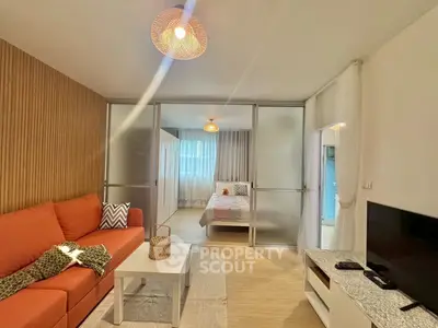 Modern living room with cozy sofa and stylish bedroom separated by sliding doors.