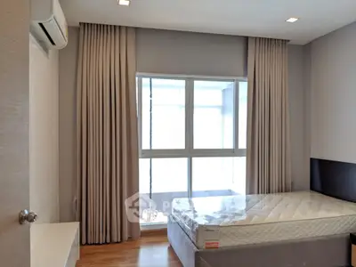 Modern bedroom with large window and natural light, featuring a comfortable bed and elegant curtains.