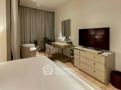 Luxurious bedroom with modern decor, featuring a large TV, elegant dresser, and cozy seating area.
