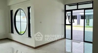 Modern interior with large circular window and glass door opening to driveway.