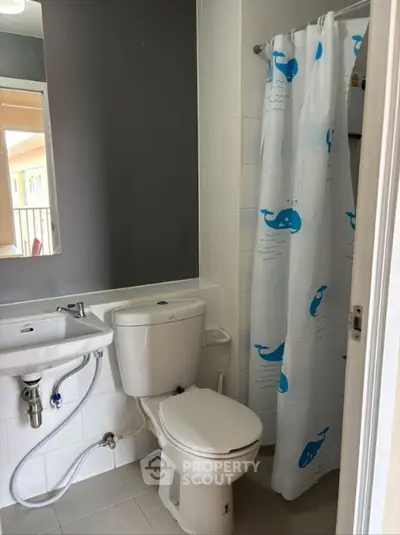 Cozy bathroom with modern fixtures and playful whale-themed shower curtain.