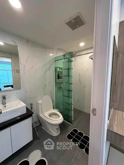 Modern bathroom with sleek design, featuring a glass shower enclosure and stylish vanity.