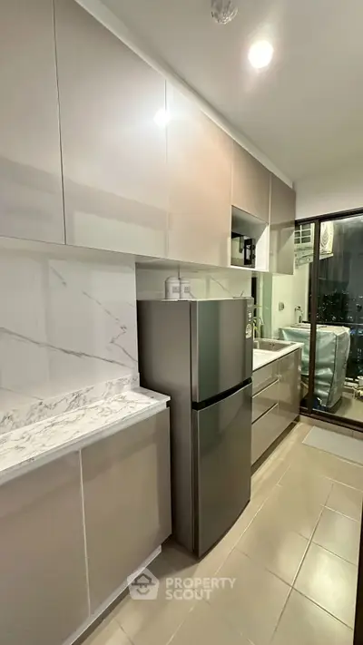 Modern kitchen with sleek cabinets and stainless steel fridge in a stylish apartment.