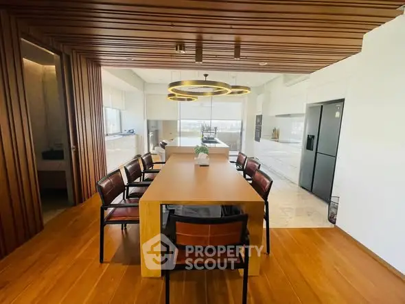 Modern dining area with wooden accents and stylish lighting in open kitchen layout.