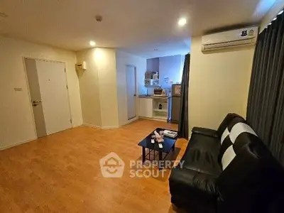 Cozy living room with wooden flooring and modern black sofa, perfect for relaxation.