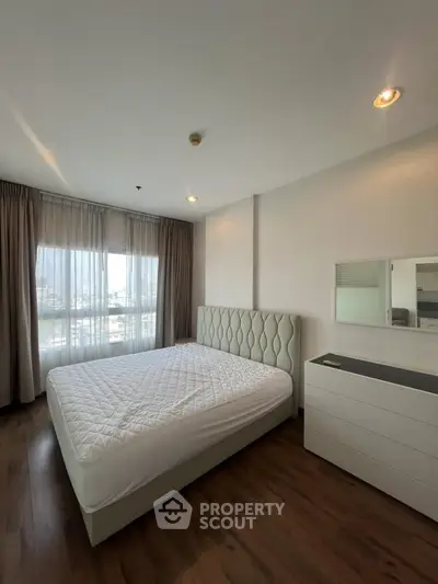 Spacious bedroom with elegant decor and large window offering city views.