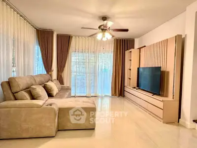 Spacious living room with modern sofa and large TV, perfect for relaxation.