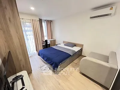Modern bedroom with cozy bed, air conditioning, and natural light from large windows.