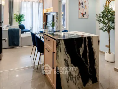 Modern open-plan kitchen and living area with elegant marble island and stylish decor.