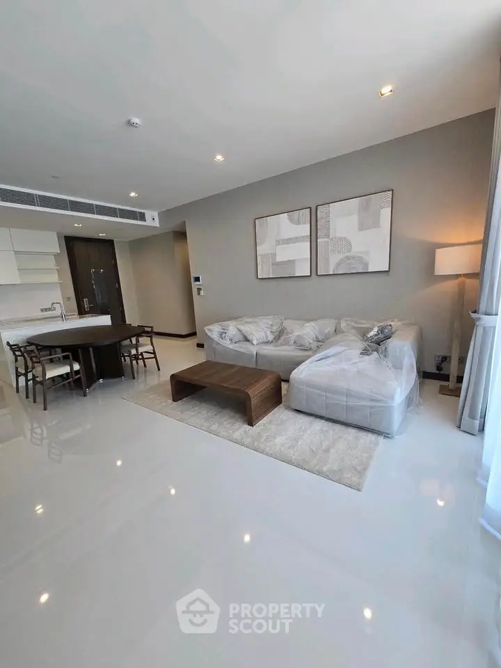 Spacious modern living room with open kitchen, sleek furniture, and elegant decor in a luxury apartment.