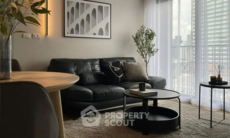 Stylish modern living room with black leather sofa, chic decor, and city view balcony.