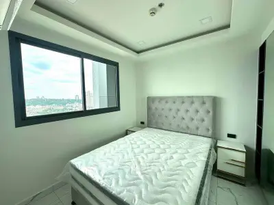 Modern bedroom with large window and stylish bed in a high-rise apartment.