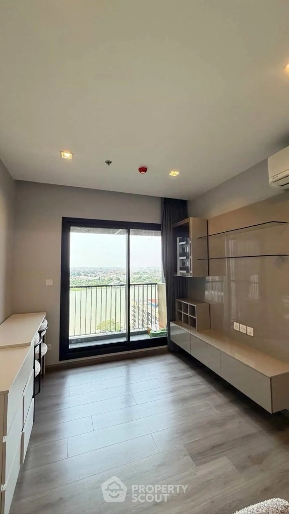 Modern living room with large window and balcony view, featuring sleek built-in storage and stylish flooring.