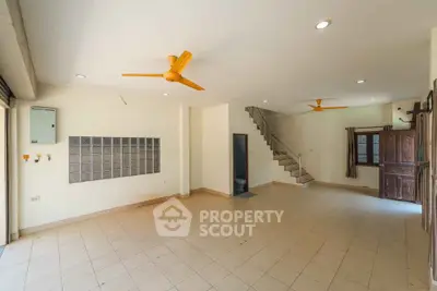 Spacious open-plan living area with ceiling fans and staircase, ideal for modern family living.