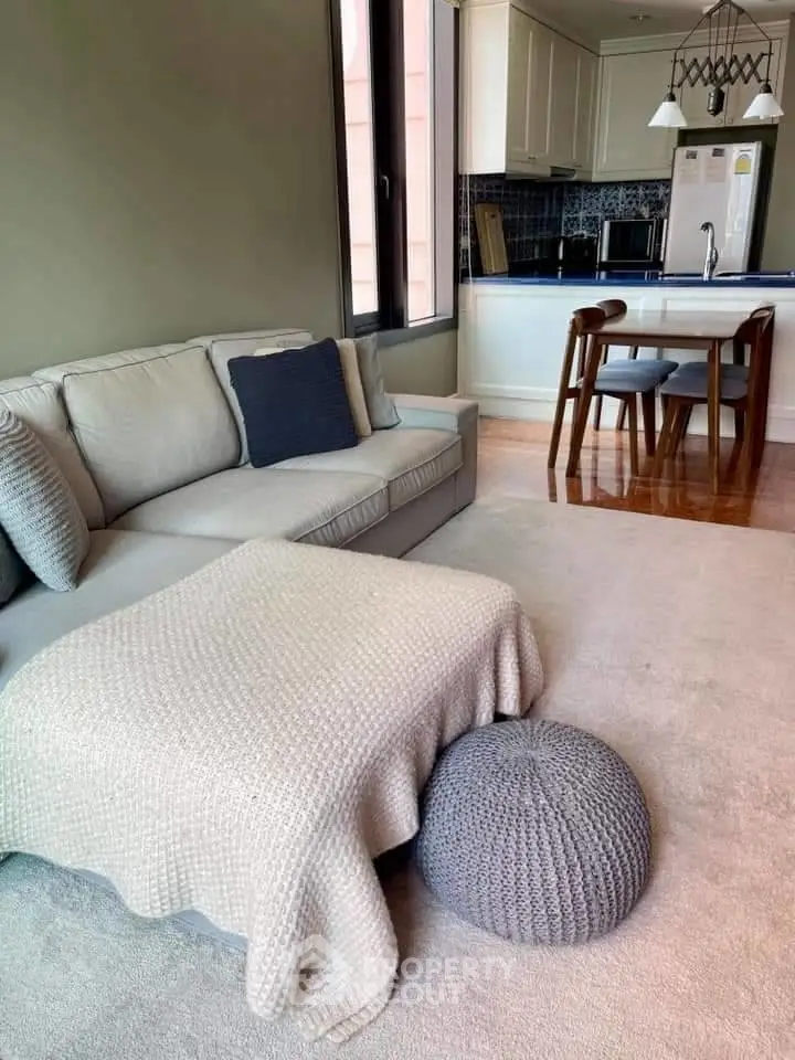 Cozy living room with modern kitchen, featuring a plush sofa and stylish decor.