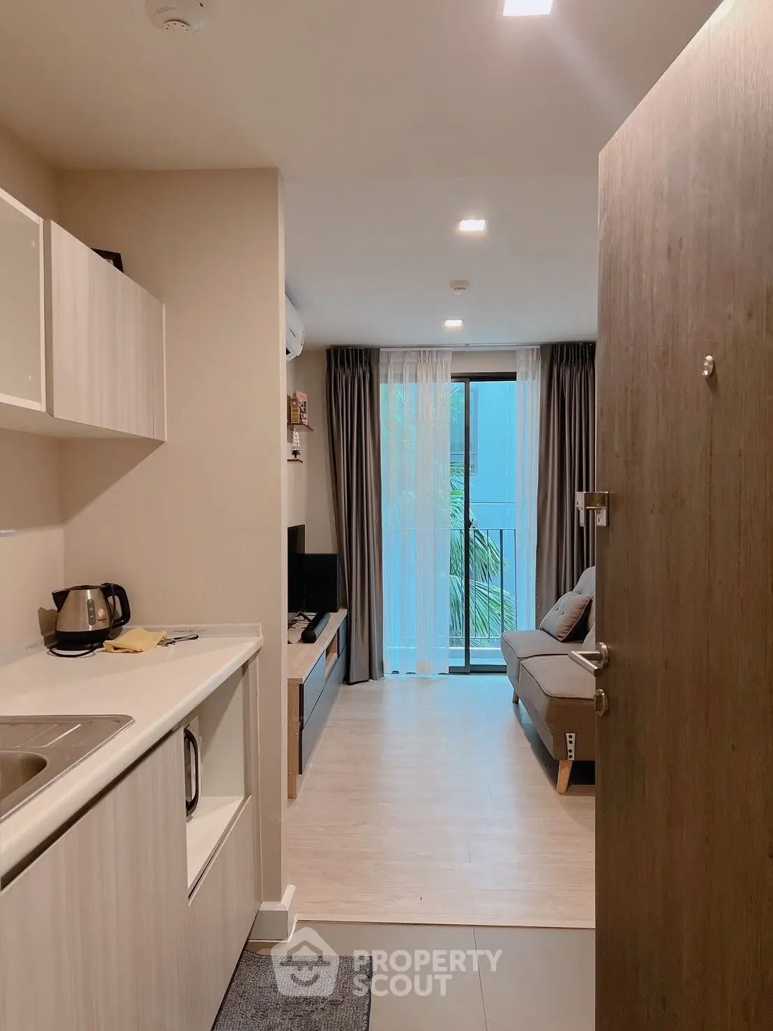 Modern open-plan living room with kitchenette and balcony view