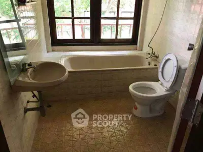 Charming bathroom with bathtub and large window offering natural light and garden view.