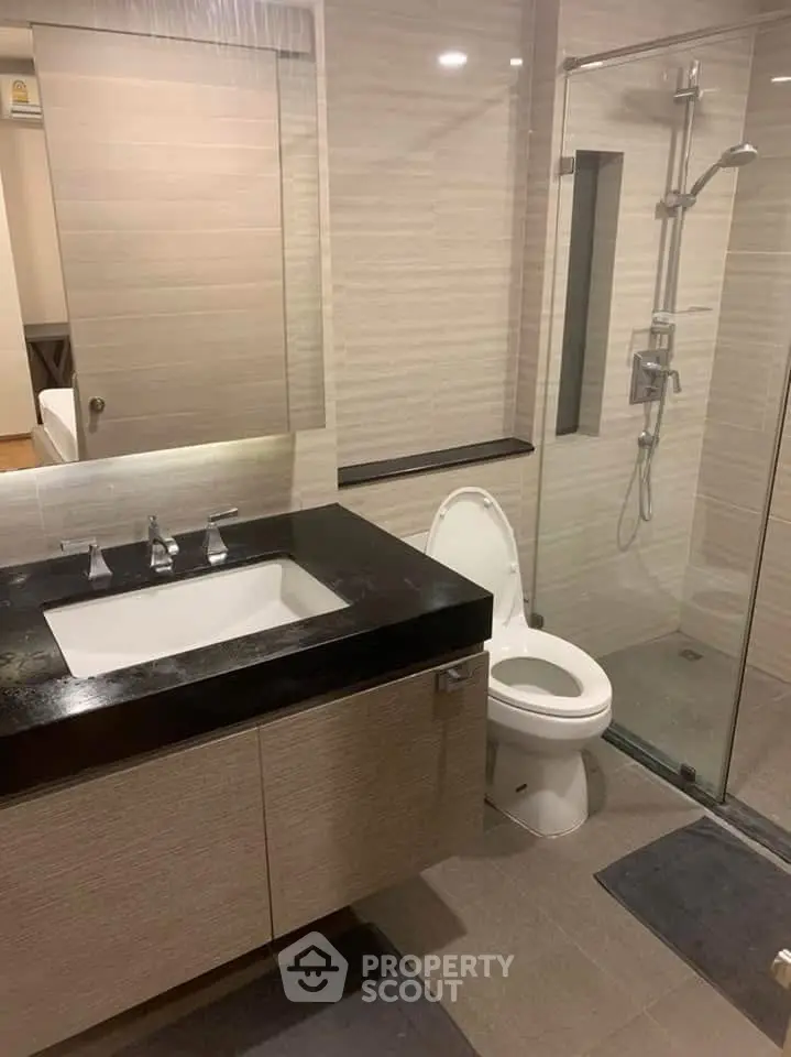 Modern bathroom with glass shower and sleek vanity in contemporary apartment.