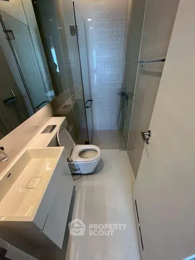 Modern bathroom with sleek design, featuring a glass shower enclosure and contemporary fixtures.