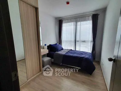 Modern bedroom with large window and stylish decor in a contemporary apartment.