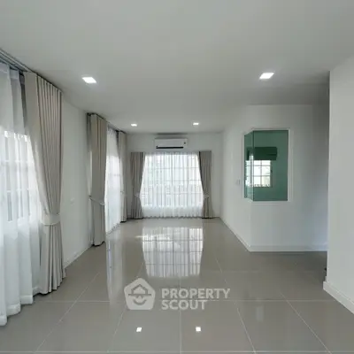 Spacious modern living room with large windows and elegant curtains