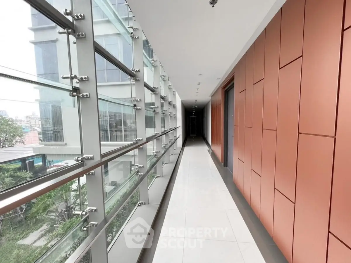 Modern corridor with glass walls and sleek design in a contemporary building.