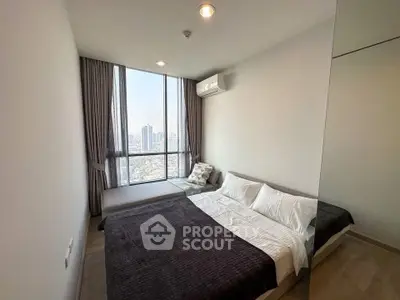 Modern bedroom with large window offering stunning city views and cozy furnishings.