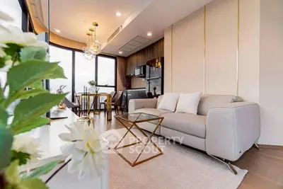 Luxurious modern living room with elegant decor and open kitchen layout, featuring large windows and stylish furniture.