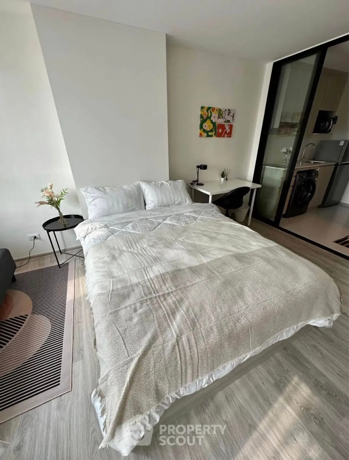 Modern bedroom with cozy bed and adjacent kitchen area, perfect for urban living.