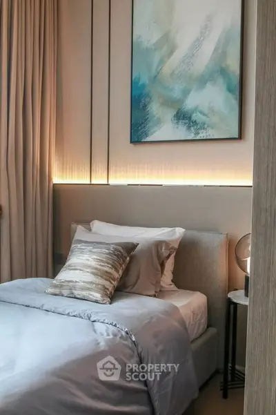 Elegant bedroom with modern decor and ambient lighting, featuring a cozy bed and stylish artwork.