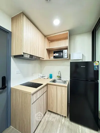 Modern compact kitchen with sleek appliances and wooden cabinetry in a stylish apartment.