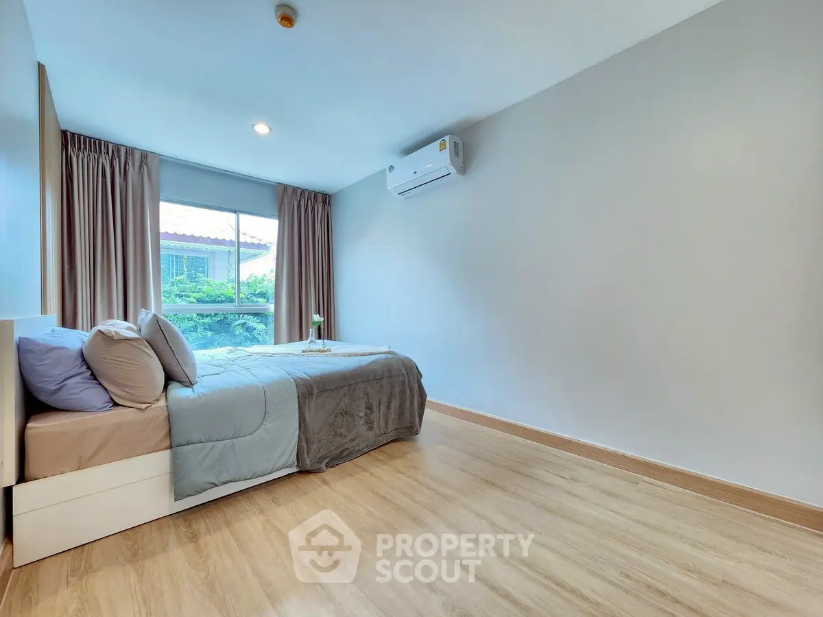 Spacious bedroom with modern decor and large window offering natural light.