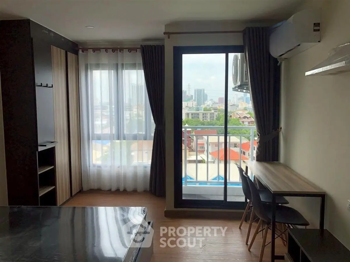 Modern apartment interior with large windows and city view, featuring sleek furniture and natural light.