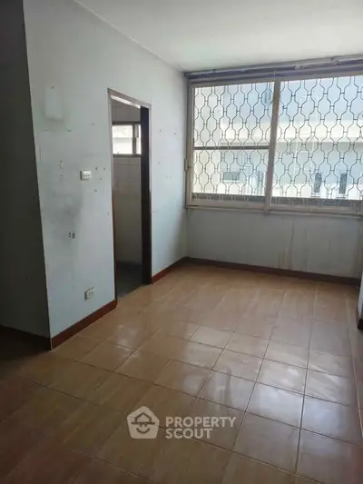 Spacious room with large window and tiled floor, ideal for customization.