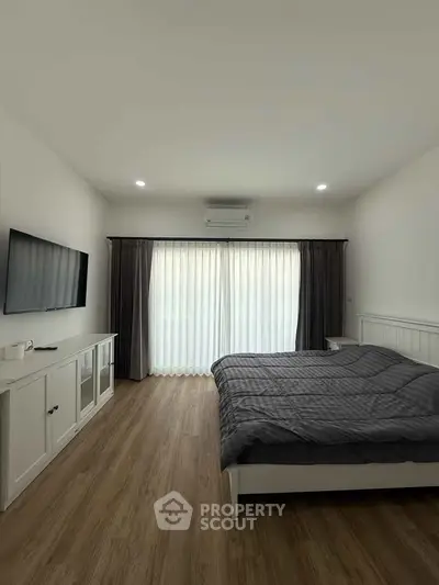 Spacious bedroom with modern decor and large window for natural light