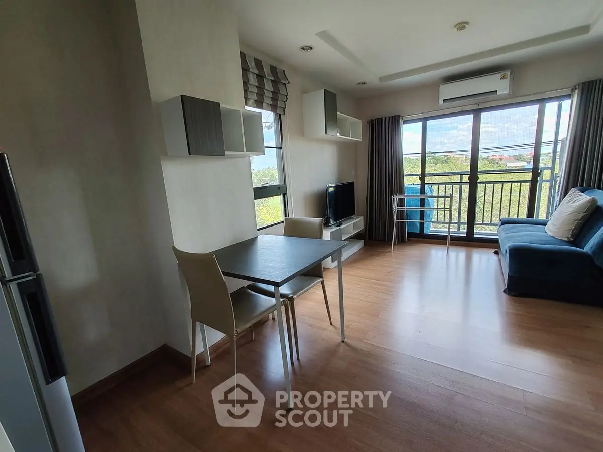 Modern living room with balcony and scenic view, featuring sleek furniture and natural light.
