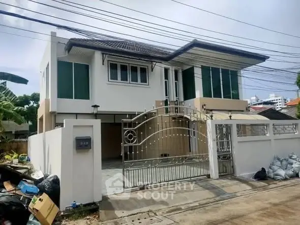 Modern two-story house with gated entrance and sleek design in suburban neighborhood.