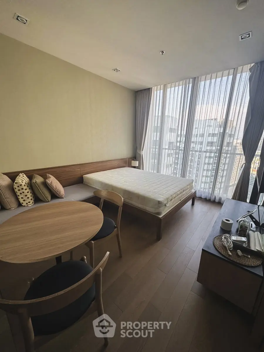 Modern bedroom with large windows and stylish furniture in a high-rise apartment.
