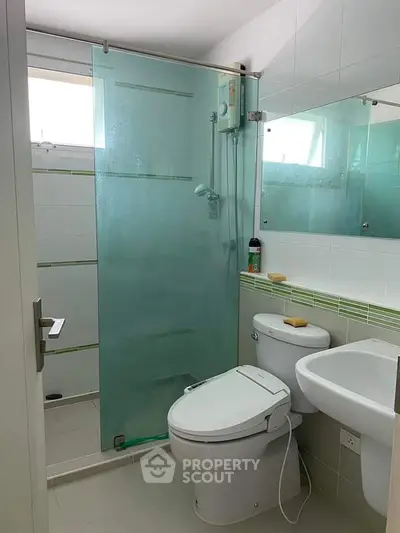 Modern bathroom with glass shower, white fixtures, and sleek design.